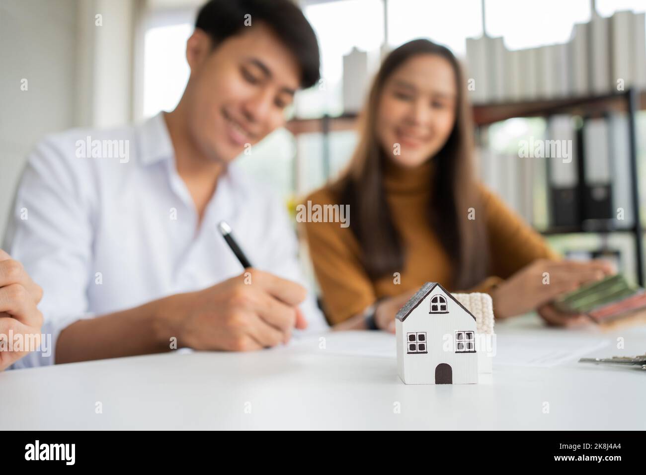 Client signs home loan document to buy homes with real estate property agent or lawyer. Real estate agent and customer signing contract to buy a house Stock Photo
