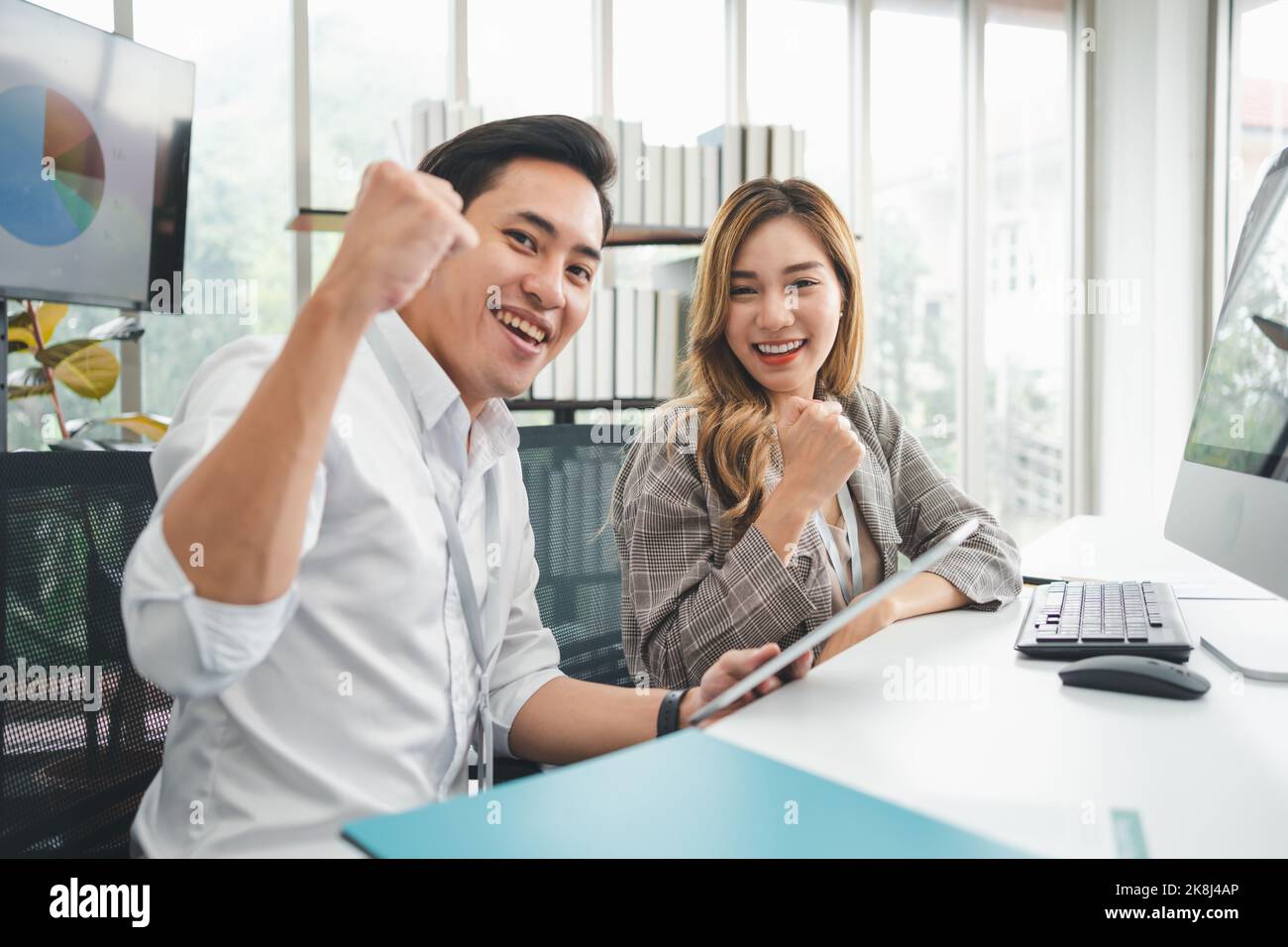 Excited young Asian startup business team celebrate successful and victory and hand up at office and looking at camera, happy euphoric proud Asian mal Stock Photo