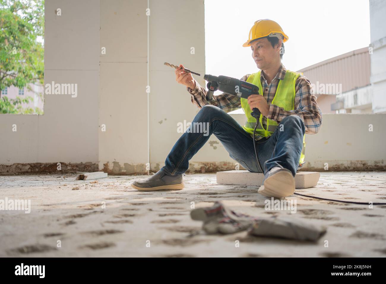 Construction worker Using an electric jackhammer to drill perforator equipment making holes before pouring the floor to be strong at construction site Stock Photo