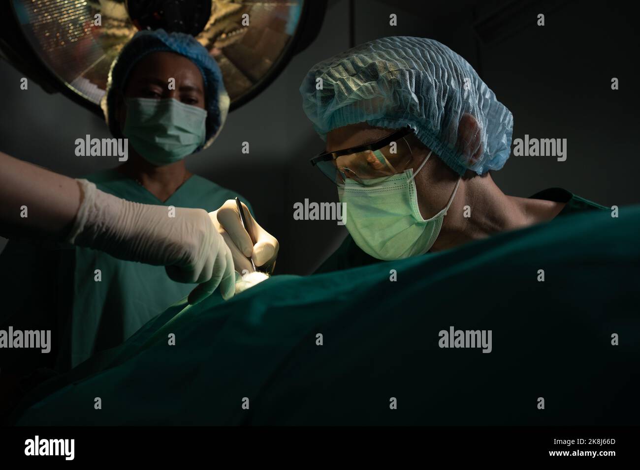 Asian Professional surgeons team performing surgery in the operating room, surgeon, Assistants, and Nurses Performing Surgery on a Patient, health car Stock Photo