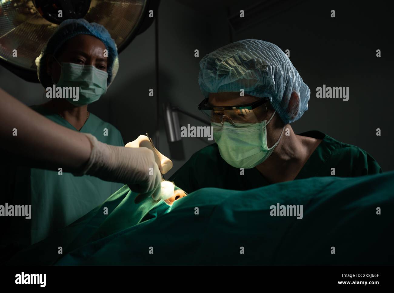 Asian Professional surgeons team performing surgery in the operating room, surgeon, Assistants, and Nurses Performing Surgery on a Patient, health car Stock Photo