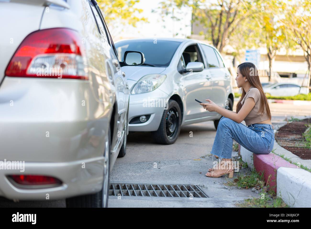 Woman drivers call insurance after a car accident before taking pictures and sending insurance. Online car accident insurance claim idea after submitt Stock Photo