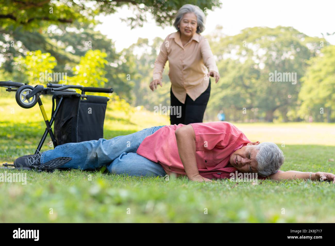 Asian senior man falling down from wheelchair on lying floor after trying push the wheelchair forward and Crying in pain and asking someone for help. Stock Photo