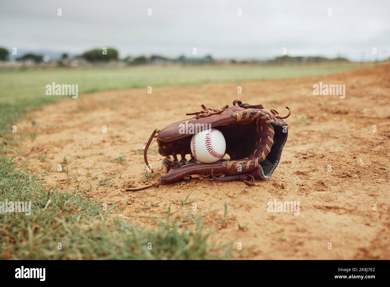 Sports, baseball gloves and field ball on dirt floor after game, competition or practice match for fitness, exercise or health. Softball pitch Stock Photo