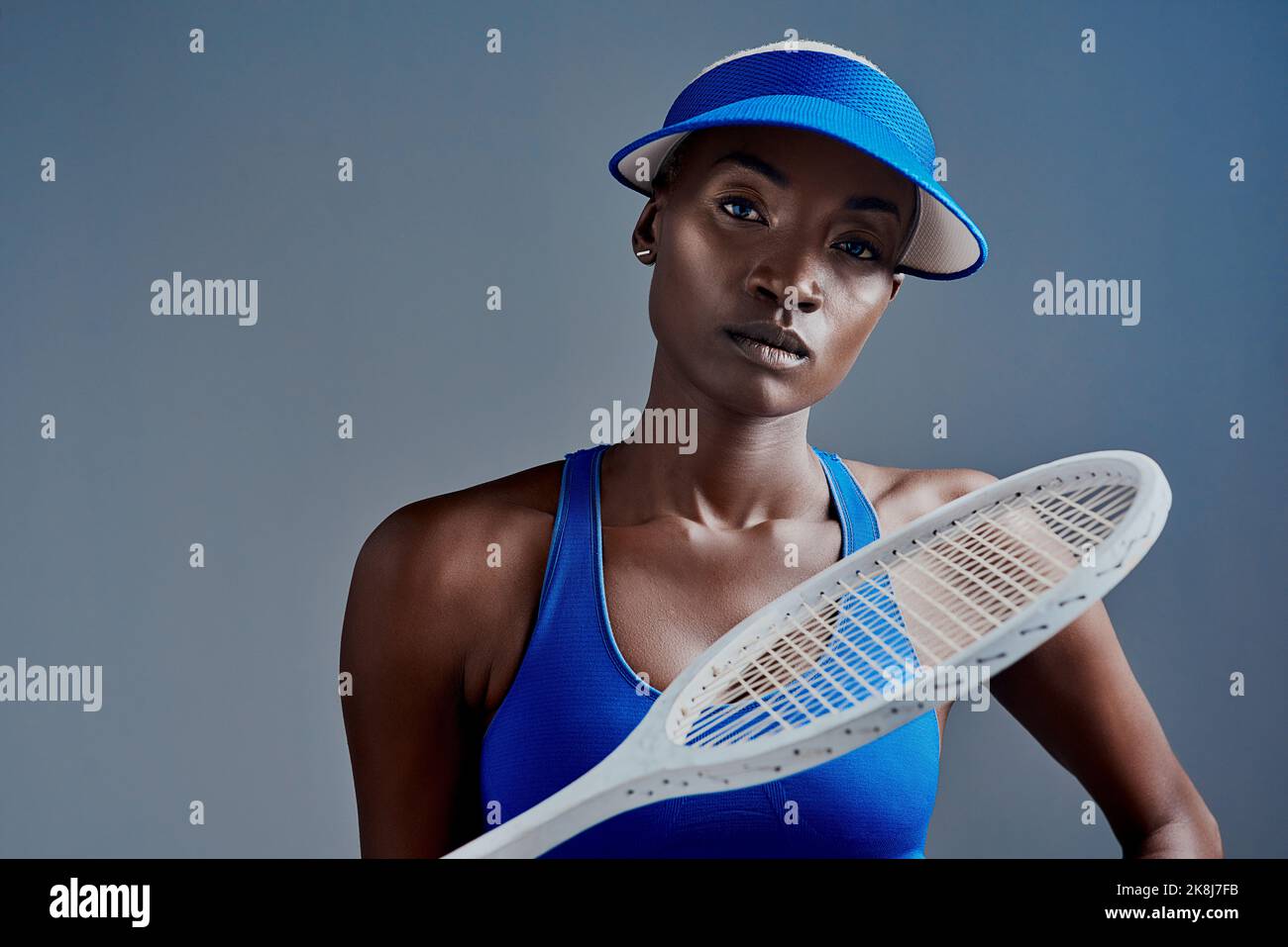 Try your best to be the best. Studio shot of a sporty young woman posing with a tennis racket against a grey background. Stock Photo