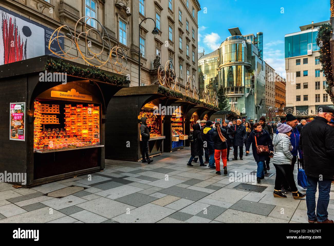 People walking along illuminated  kiosks selling souvenirs and Christmas decorations in Vienna, Austria. Stock Photo