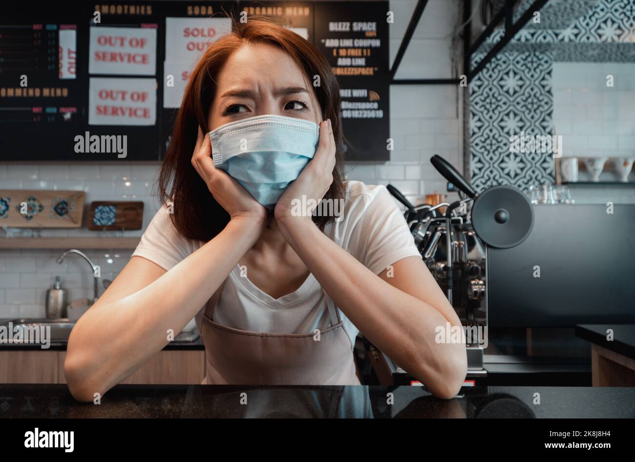 Asian woman coffee shop business owner Stressed and disappointed from The effects of the coronavirus pandemic resulting in business losses Stock Photo