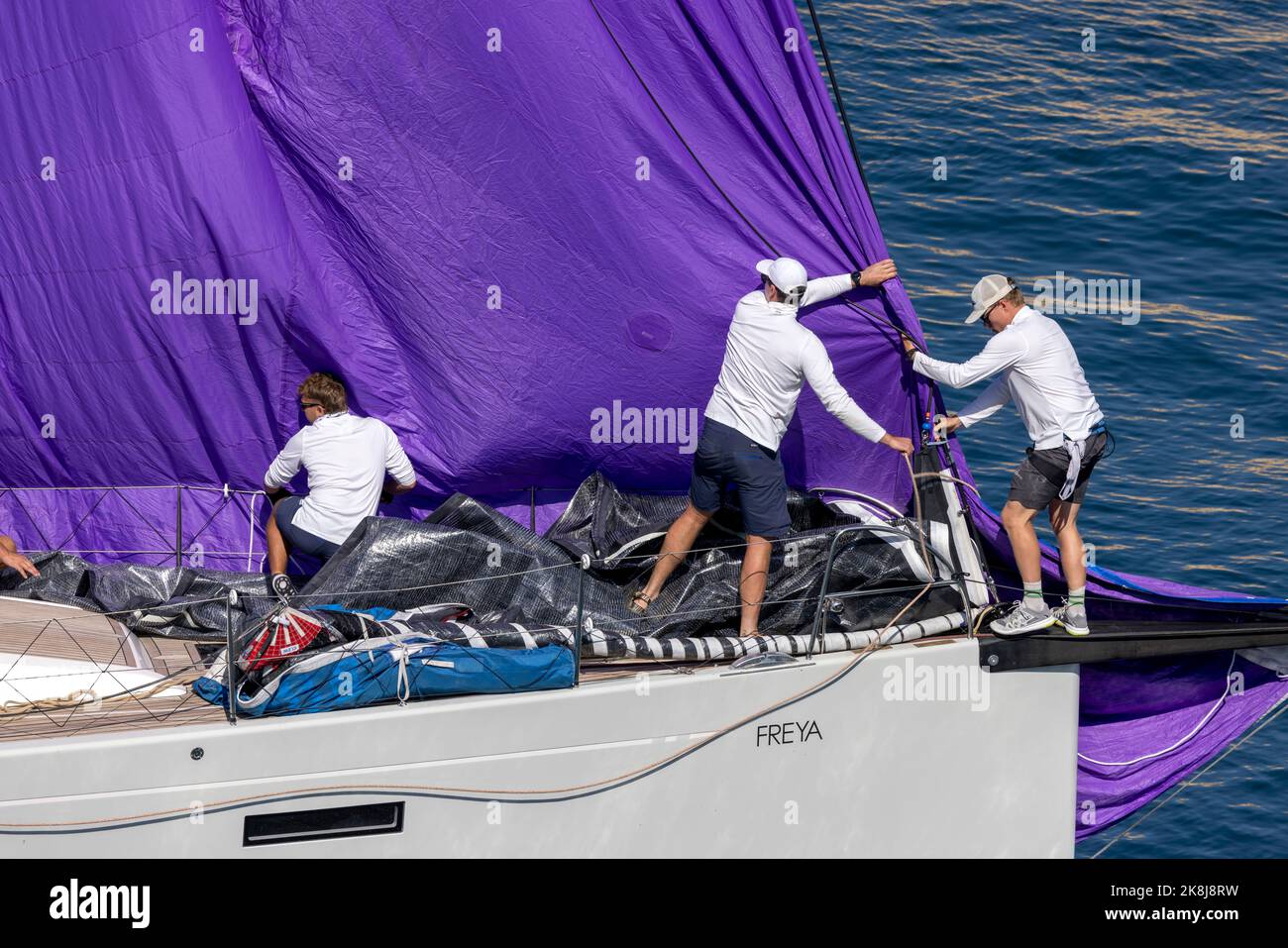 Crew on a competing yacht in the Middle Sea Race 2022 preparing their vessel on the start of the race in nearly perfectly calm conditions. Stock Photo
