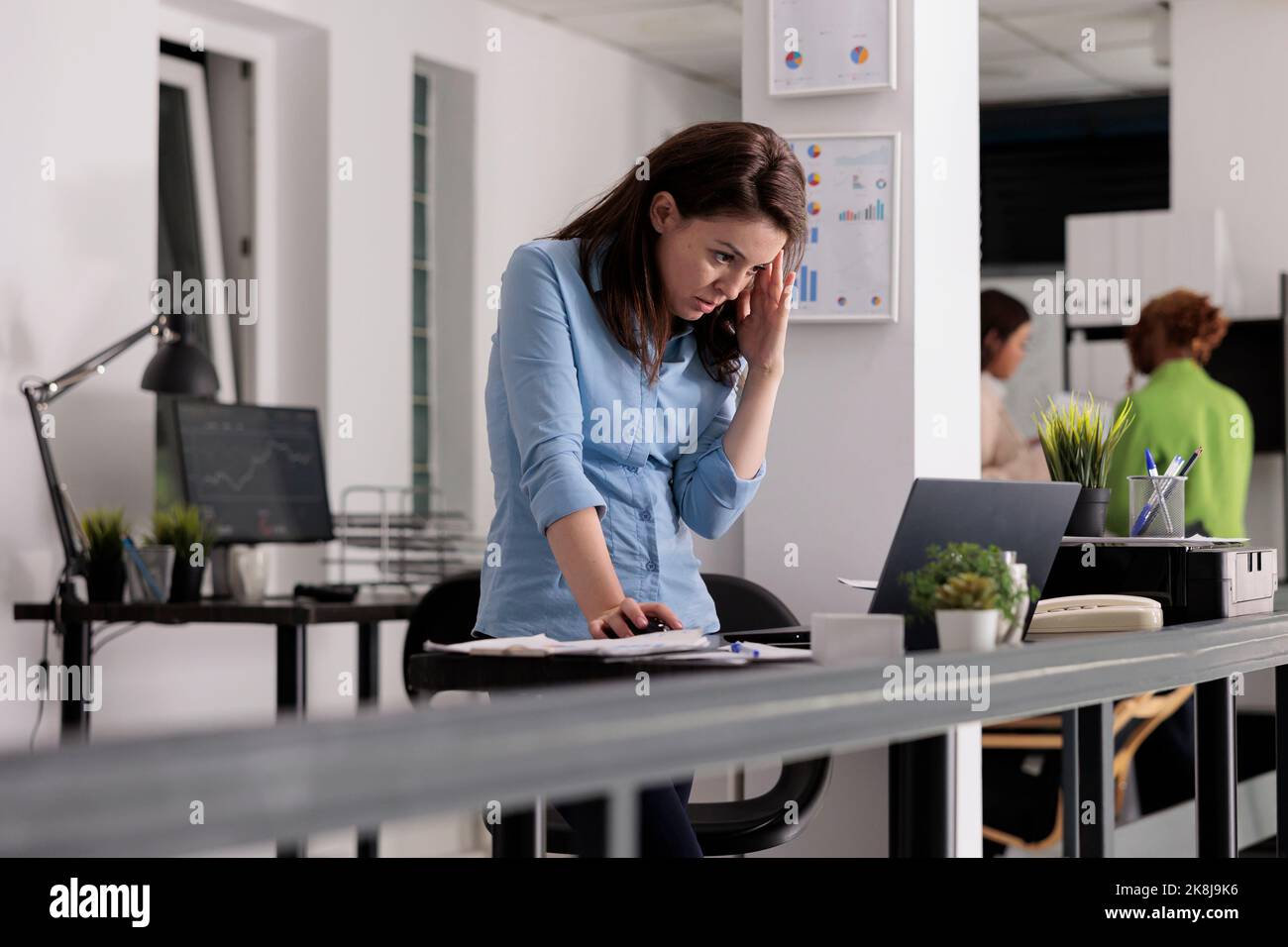 Sad employee having headache, busy manager tired from work, exhausted woman in coworking space. Office worker suffering from migraine symptom, frustrated person feeling unwell, touching temples Stock Photo