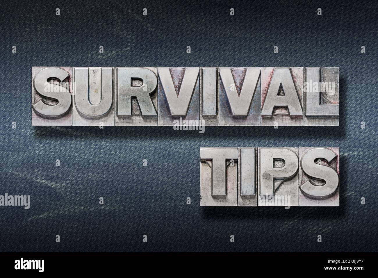 survival tips phrase made from metallic letterpress on dark jeans background Stock Photo