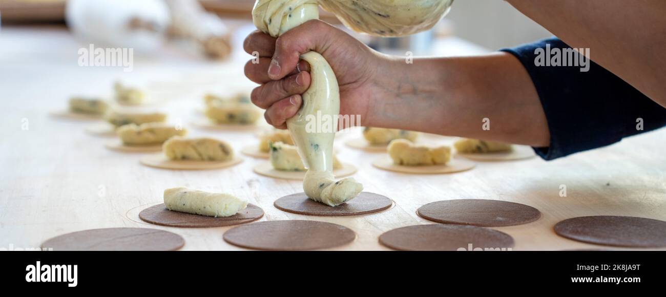 Horizontal banner or header with woman prepare fresh made ravioli inside pasta factory. Using a pastry bag or sac a poche to make stuffed pasta raviol Stock Photo