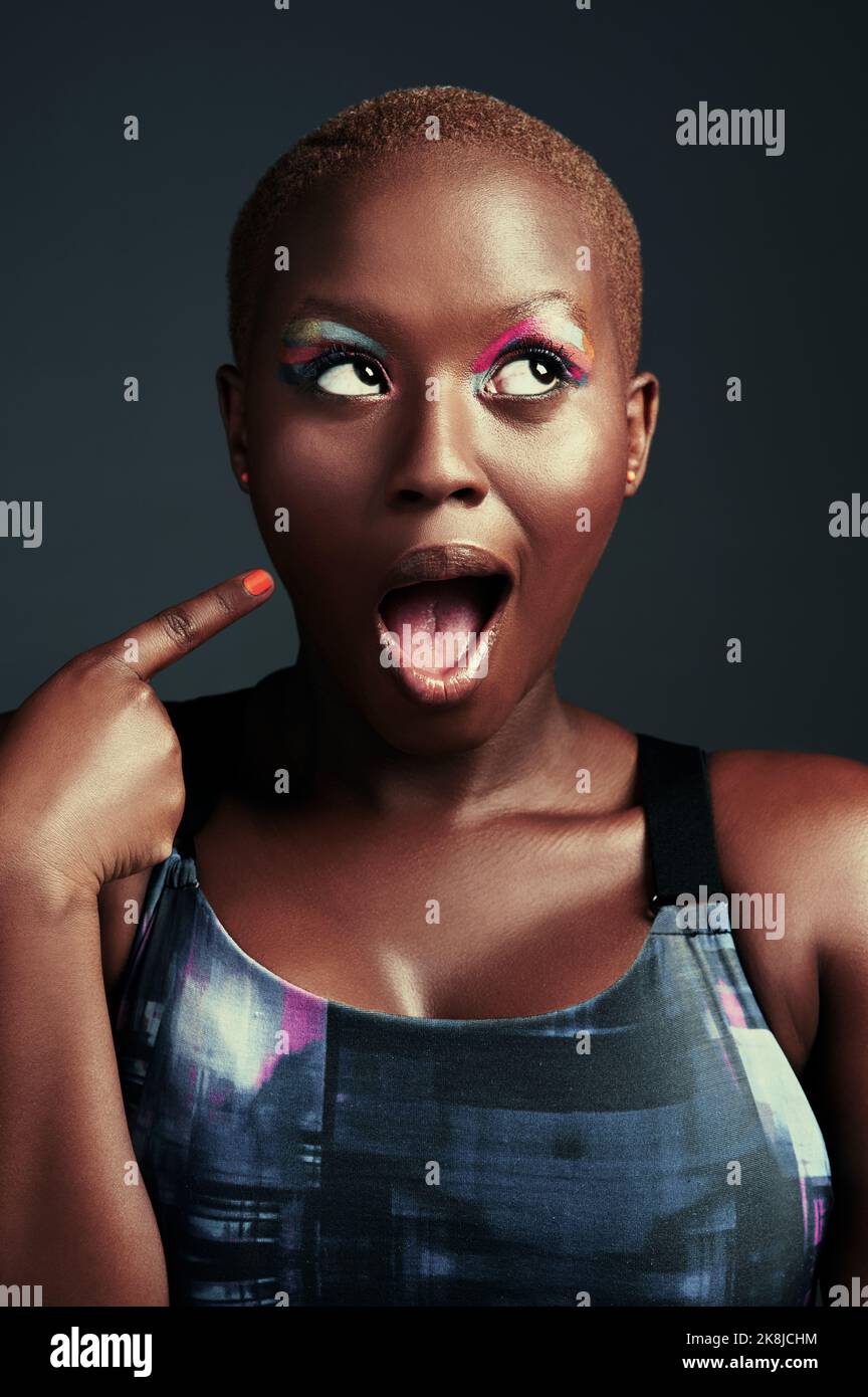 Shes full of colorful thoughts. a beautiful woman wearing colorful eyeshadow while posing against a grey background. Stock Photo