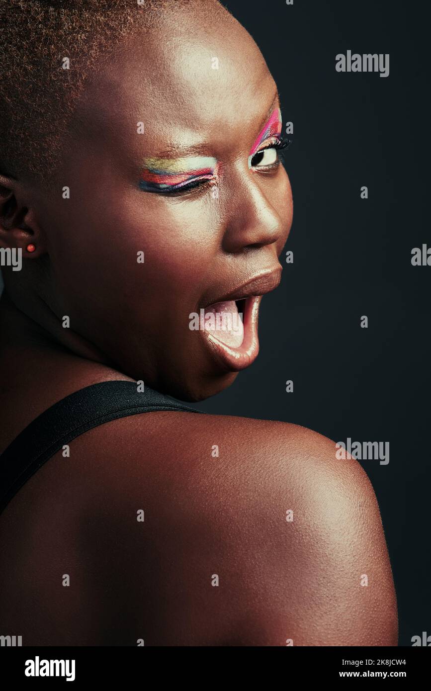 She has a colorful personality. a beautiful woman wearing colorful eyeshadow while posing against a grey background. Stock Photo