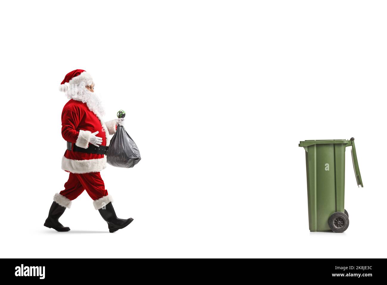 Full length profile shot of santa claus walking towards a bin and ...