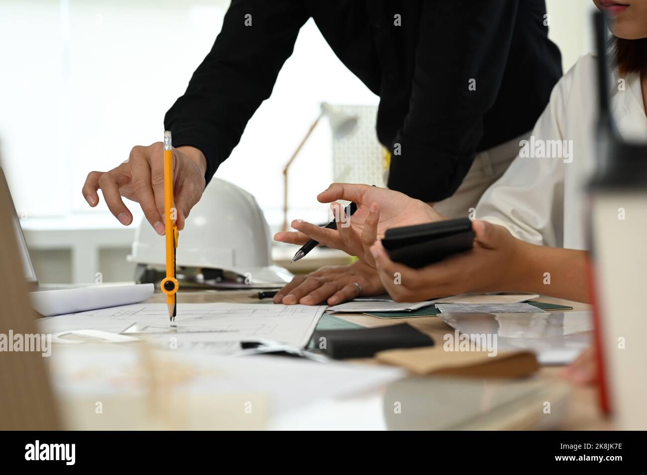Young architect using divider compass tools on blueprint, working on ...