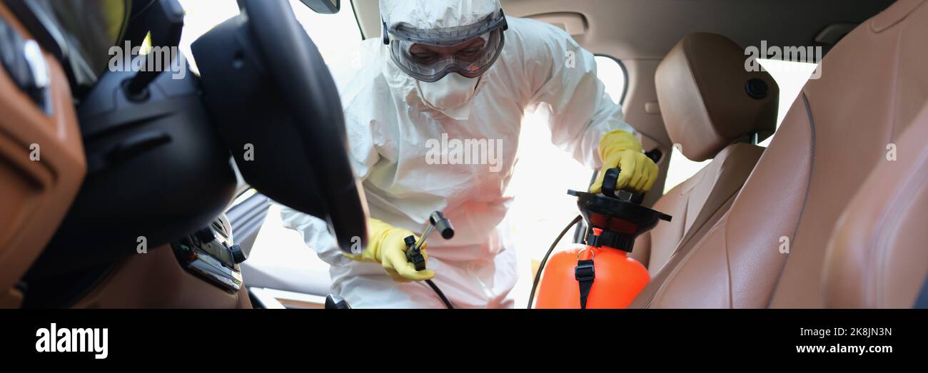 Worker cleanse car interior with spray disinfectant in container Stock Photo