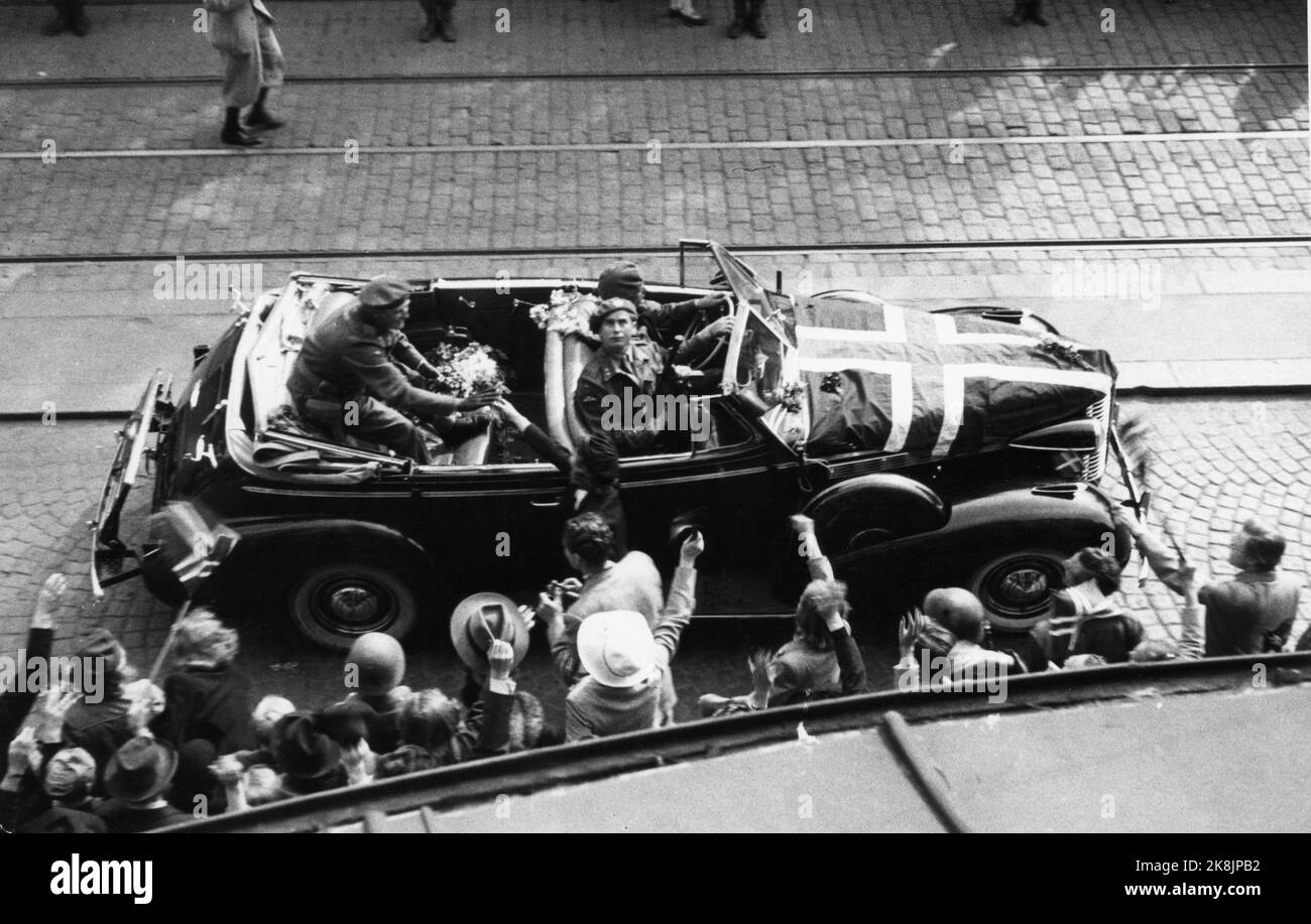 Oslo, May 13, 1945. Release: Crown Prince Olav receives a warm welcome when he returns to Norway after the war. He was met by large crowds upon arrival. Here is the car with the Crown Prince at Karl Johan. He gets flowers from people along the route. In the front seat of the open car is Max Manus armed guard. Ntb archive photo / ntb Stock Photo