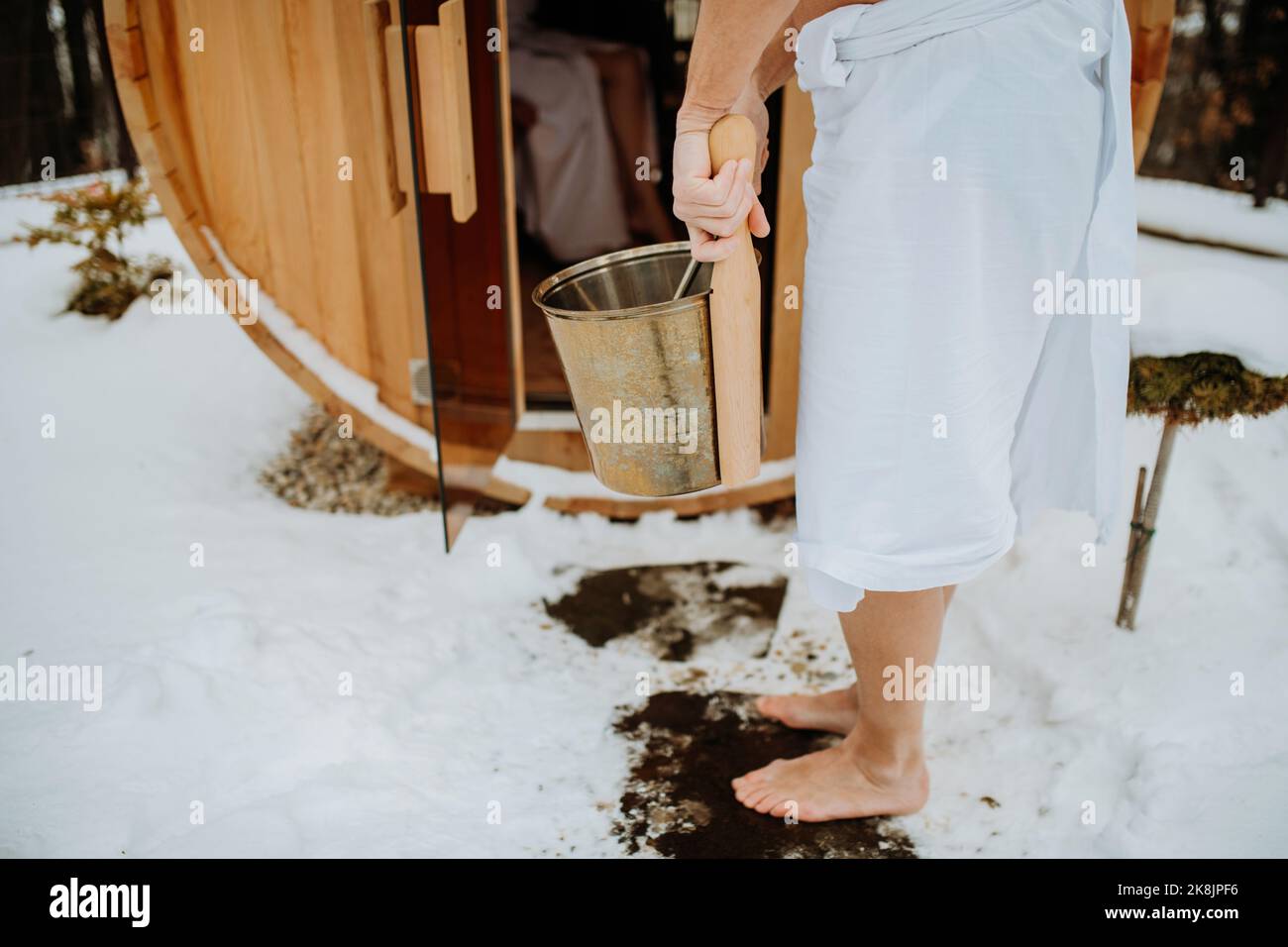 Low angle view of seniors entering in to outdoor hot tub with pail. Stock Photo