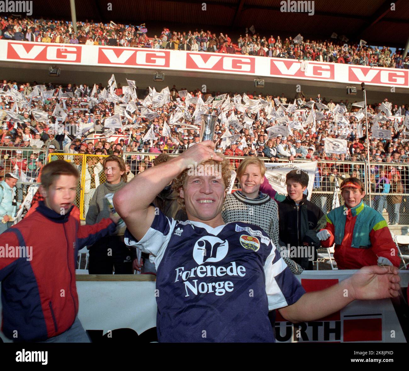 Oslo 19911020: Cup final 1991. Rosenborg (RBK) - Strømsgodset (SIF) (2-3). Ullevaal Stadium. Picture: Strømsgodset hero Odd Johnsen Jøgler smiling with the trophy (on his head) after the cup final against Rosenborg. (In the background: Advertising for the newspaper VG.) Photo: Morten Holm / NTB / NTB Stock Photo