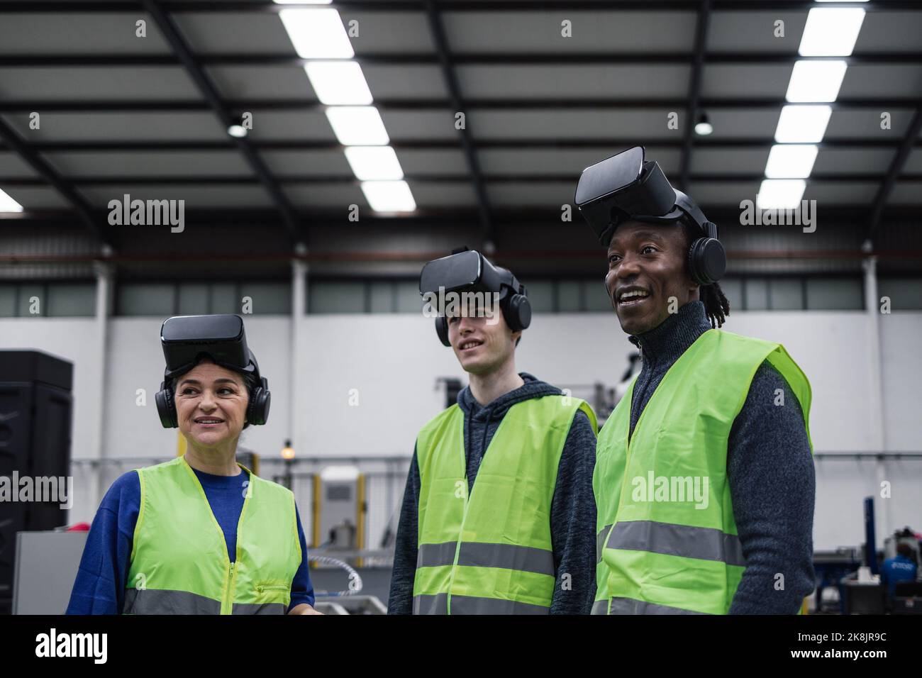 Team of engineers having simulation experience with futuristic virtual reality glasses inside robotic factory - Tech industry and metaverse concept Stock Photo