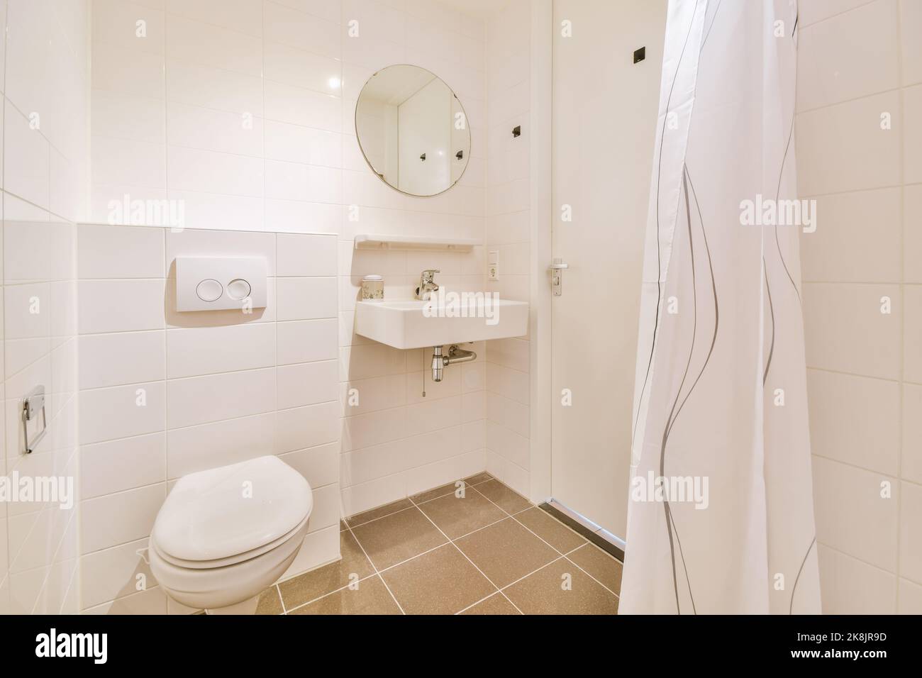 Bathroom with white tiled walls and open shower near sink and toilet in