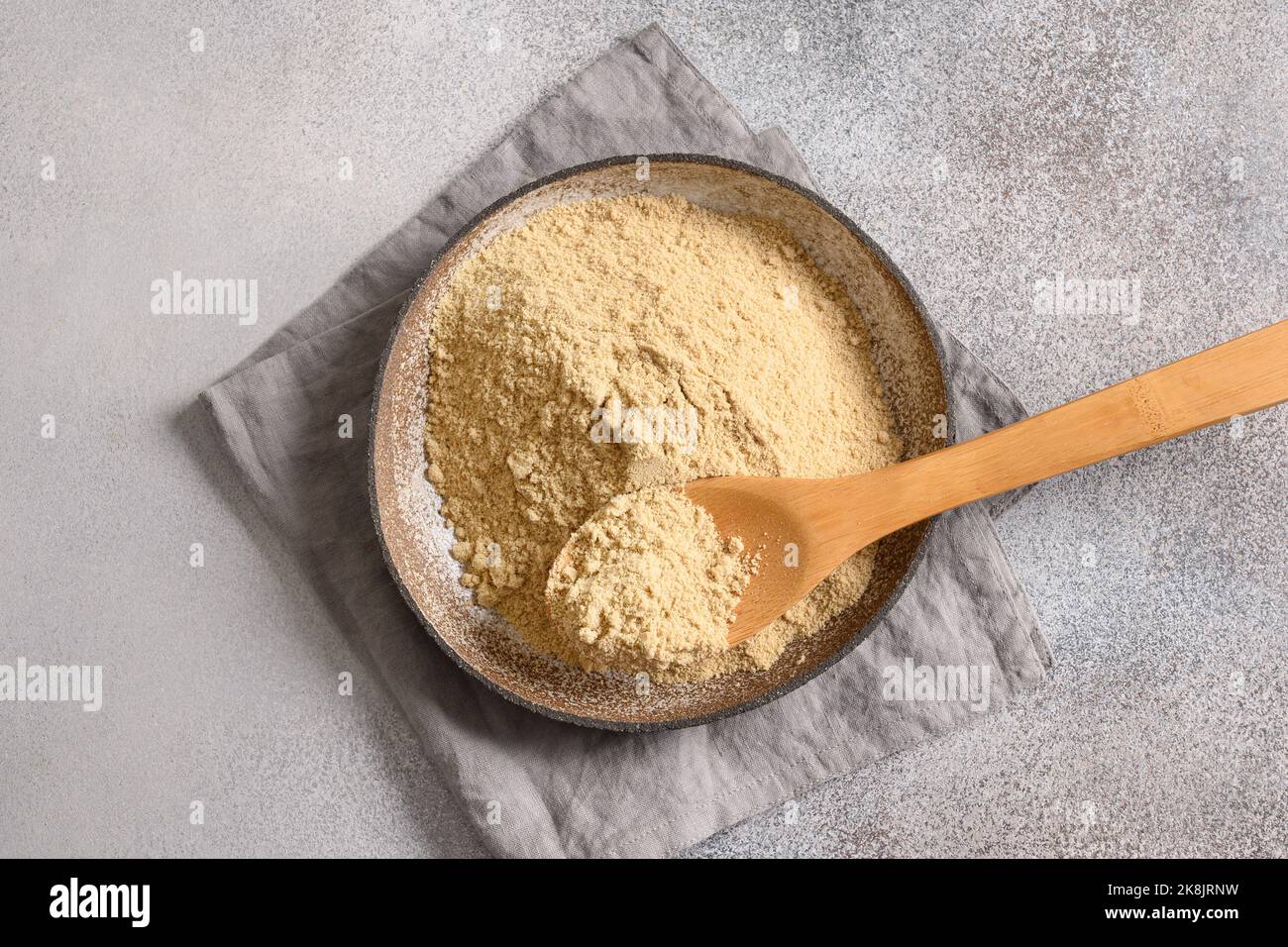 Sesame flour in bowl and white sesame seeds on gray background for cooking low carbohydrate vegan dessert. Top view. Stock Photo