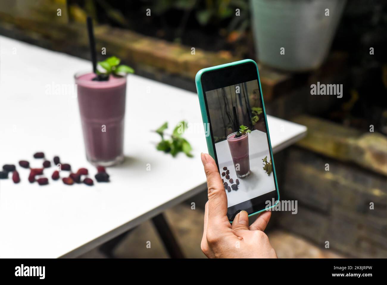 A woman taking picture of mulberry smoothie for advertisement and social media Stock Photo