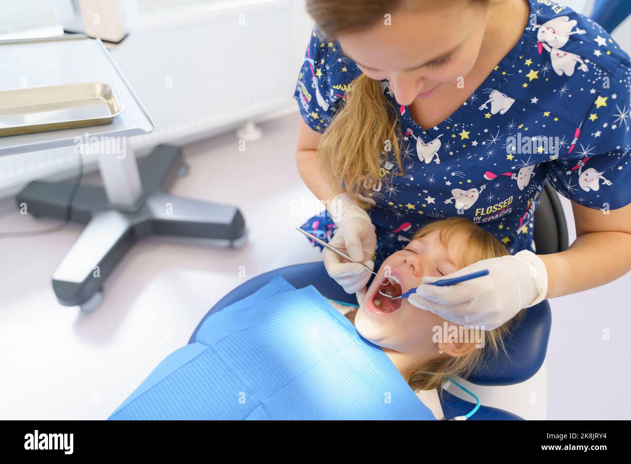 Young woman dentist doing doing preventive examination little girl. Stock Photo