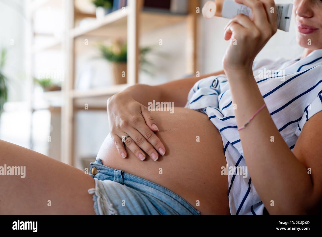 Care about perfect and smooth skin in pregnancy time. Pregnant woman using stretch mark cream