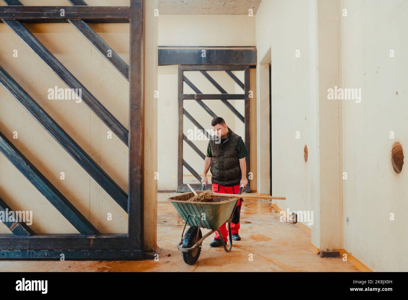 Caretaker with down syndrome in zoo pushing wheelbarrow after tidying
