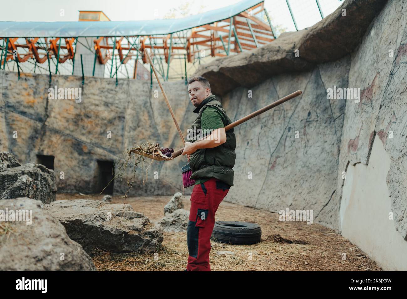 Caretaker with down syndrome in zoo cleaning animal enclosure. Concept ...