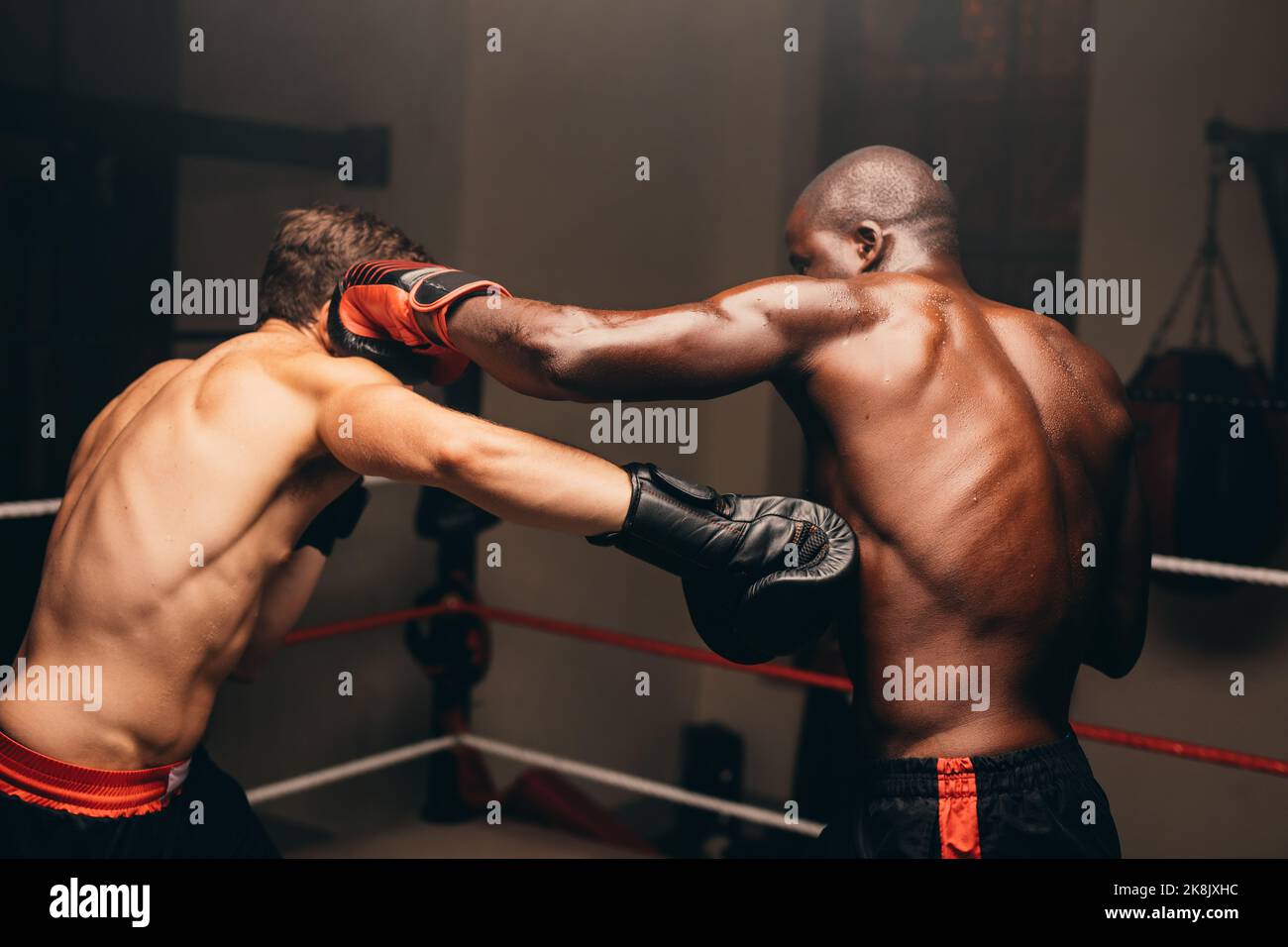 Two multiracial boxers throwing punches during a fight in a boxing ring