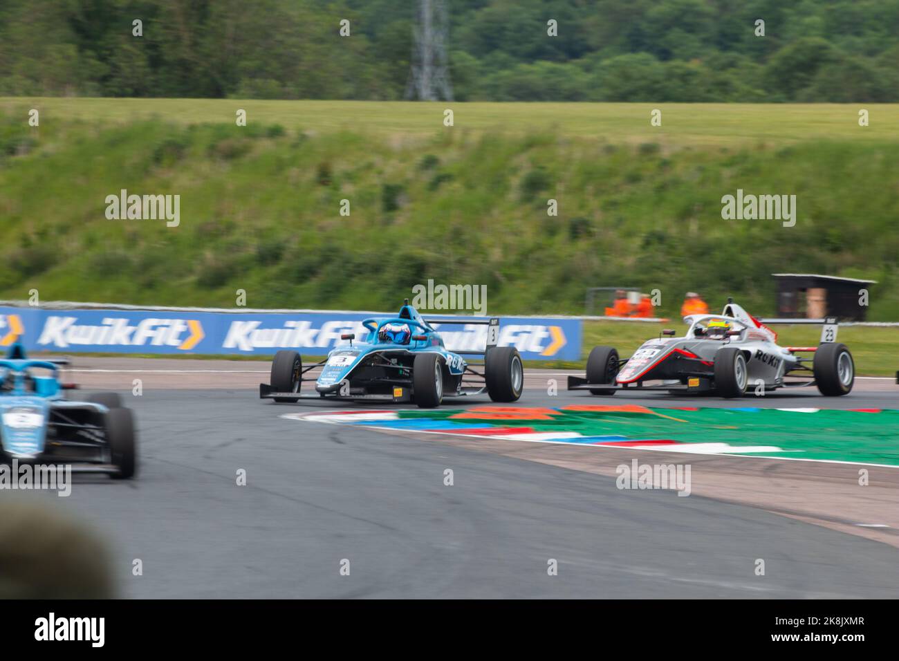 A racing track with F4 Championship cars cornering on the track at ...