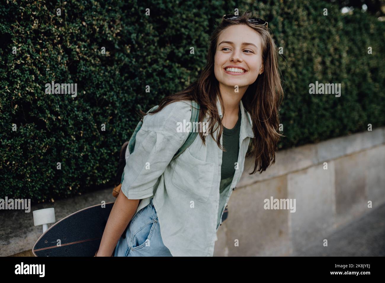 Portrait of young happy woman outdoor with skateboard. Youth culture and commuting concept. Stock Photo