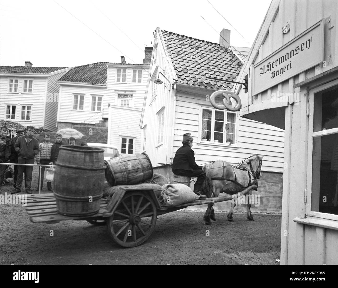 Skudeneshavn June 1967. The filming of 'Skipper Worse' was filmed in 'Søragadå' in Skudeneshavn, which has old farm houses and seahouses from the 18th century that is just as untouched to this day. The television theater will broadcast five hours of film about skipper Worse. Here we see horses with carts loaded with barrels drive through the narrow streets. Signs on the house wall 'Hermansen bakery' and a large pastry. Photo: Sverre A. Børretzen / Current / NTB Stock Photo