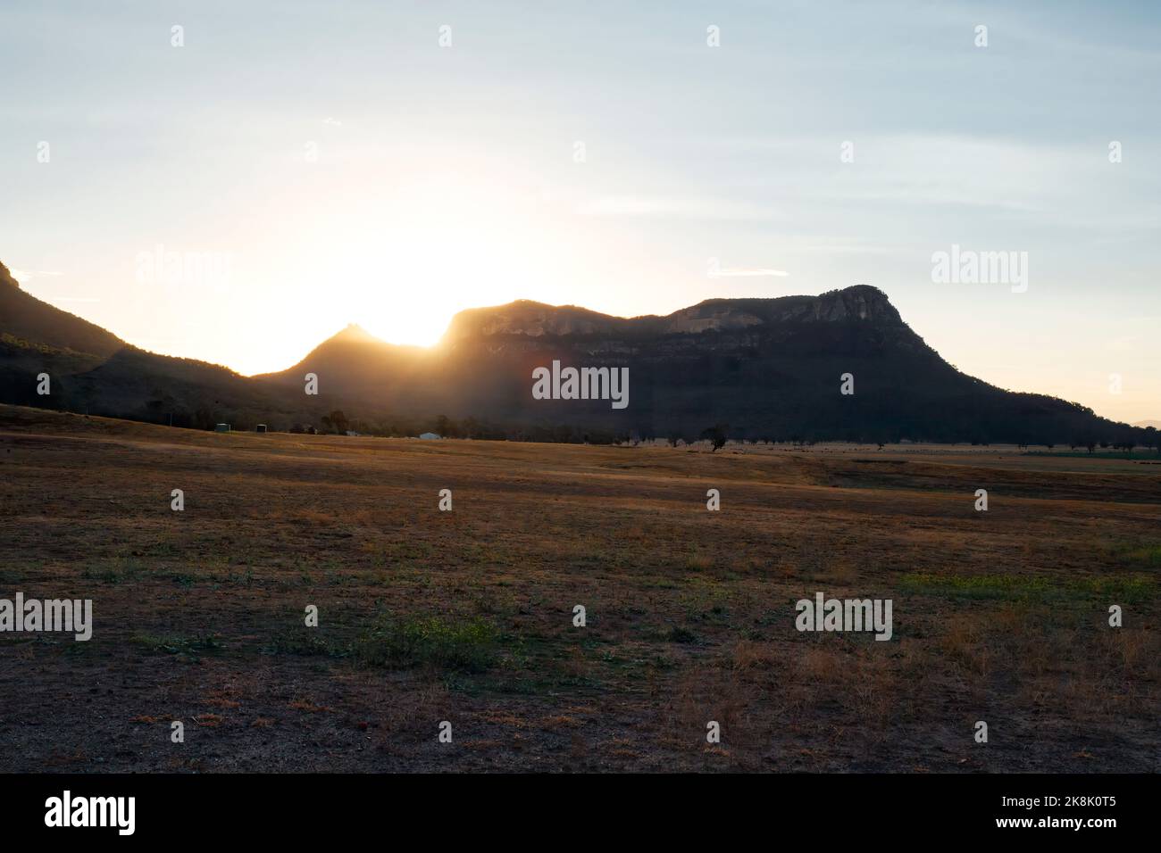 Sunset sunbeams sunburst as they hit the mountain edge in the Capertee Valley. in rural outback Australia Stock Photo