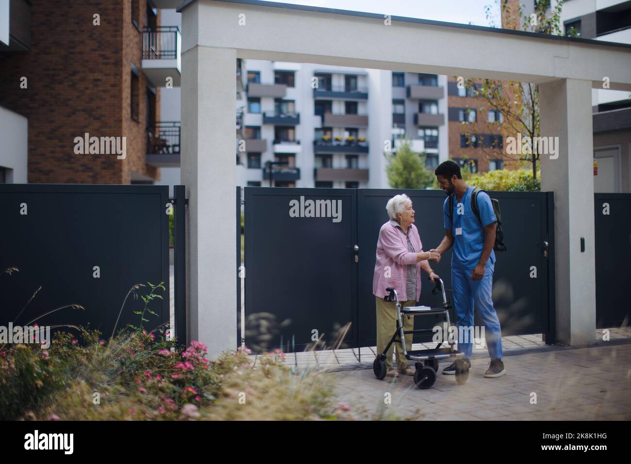 Caregiver walking with senior woman client in front of nurishing home
