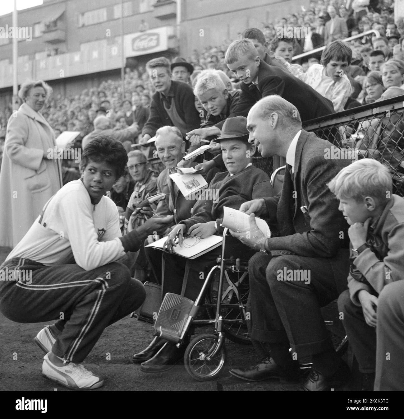 Oslo 19620828 American athletics star Wilma Rudolph, who took three gold medals during Olympic Games in Rome 1960, visits Norway. Here she writes autographs for a boy in a wheelchair, at Bislett during an athletics event. Photo: NTB / NTB Stock Photo