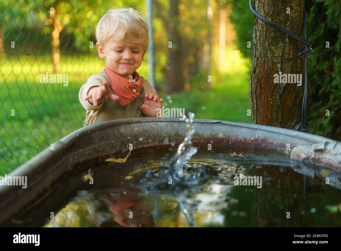 Happy little boy throwing rocks in water in their garden Stock Photo