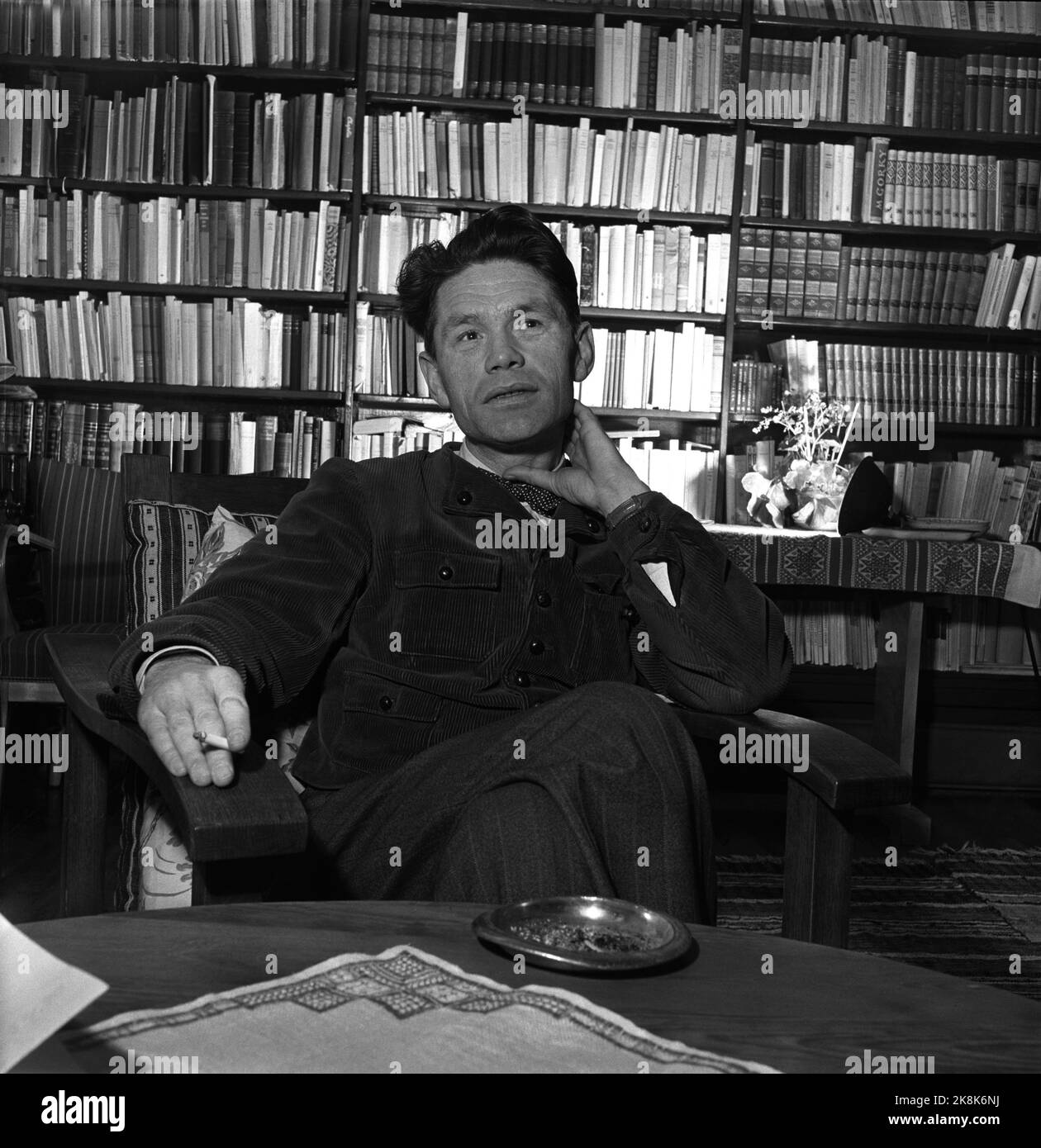 Oslo 19550212 - at the home of author and film reviewer Sigurd Evensmo. Here he sits with shelves full of books in the background. Smoker. Photo: Aage Storløkken / Current / NTB Stock Photo