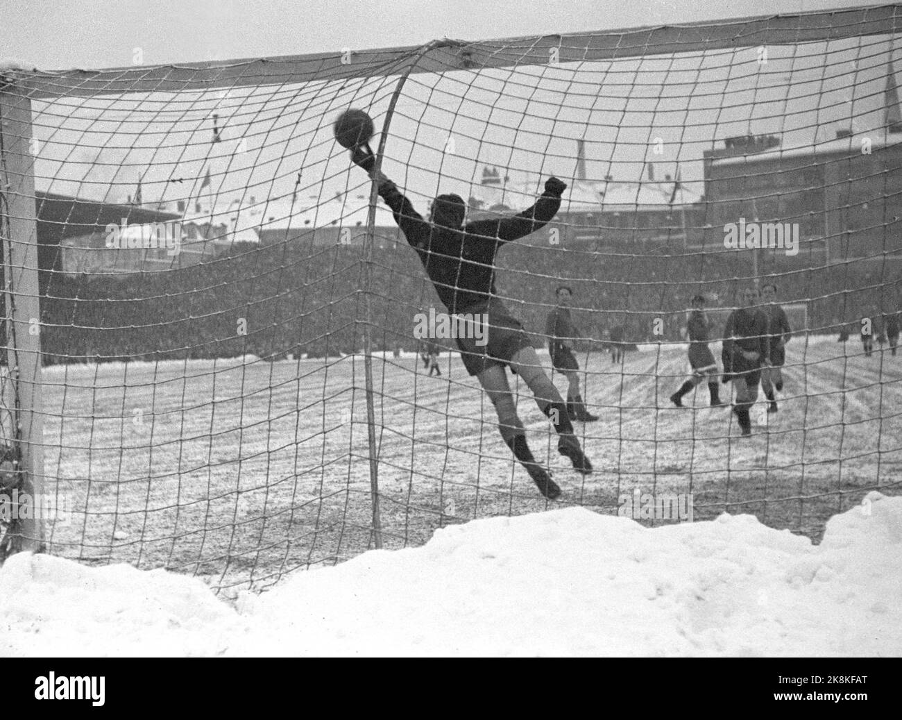 Oslo 19471115. Football in snowy weather at Bislett. The football match between Dynamo and Skeid was played on winter. Before and during the match it snowed tightly, and the grass mat was white and hard. 32,000 spectators are a record at Bislett. Here it is 'Skeids' keeper Knut Arnevaag who takes a great rescue. Photo: Current / NTB Stock Photo