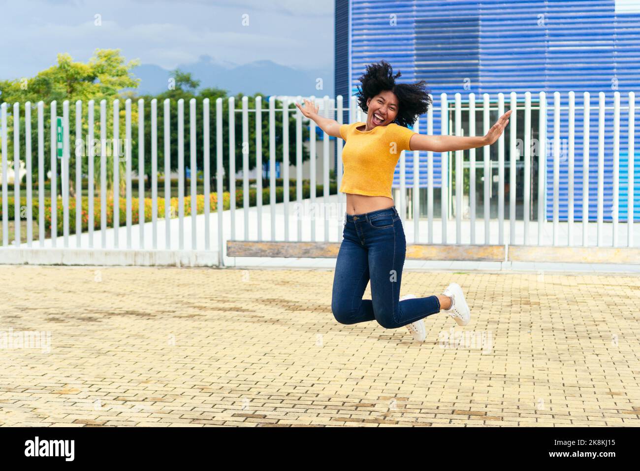 Afro woman jumping at city street Stock Photo - Alamy