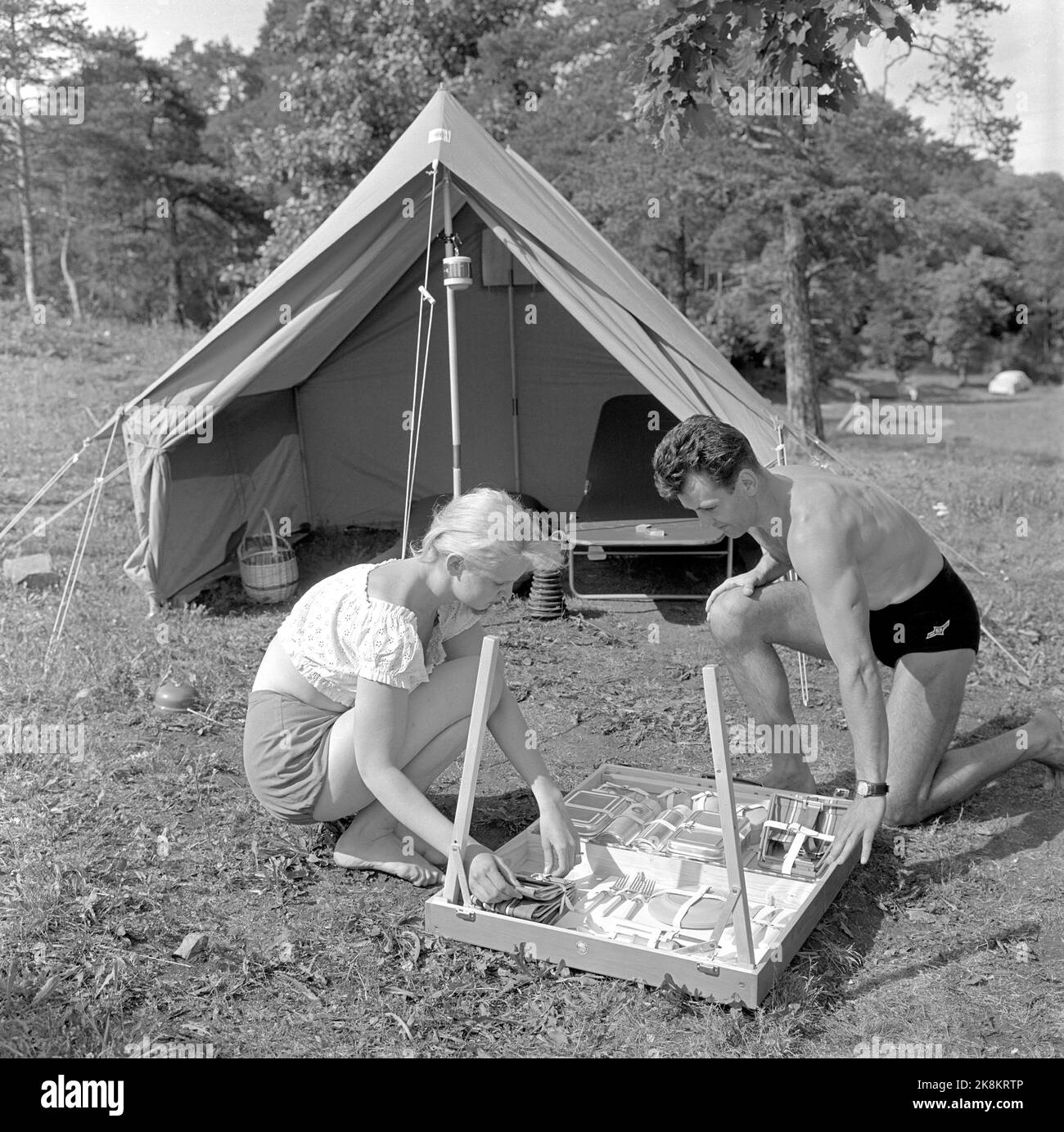 Oslo 195707: As comfortable as at home! Pictures from a report in the magazine Current from July 1957: Modern equipment for camping is demonstrated by couples on camping tour. Caption from the current: 'It can accommodate four chairs, eating equipment for four people, two thermos bottles and two aluminum food boxes. And the legs bend only into the suitcase before it is tasted again. NOK 247, you have to go out to the all-possible case.' Photo: Kaare Nymark / Current / NTB Stock Photo