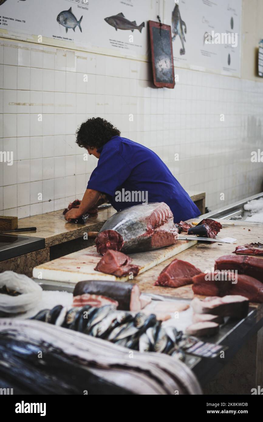 A vertical shot of the butcher cutting meat at the Farmers Market in Funchal, Madeira Island Stock Photo