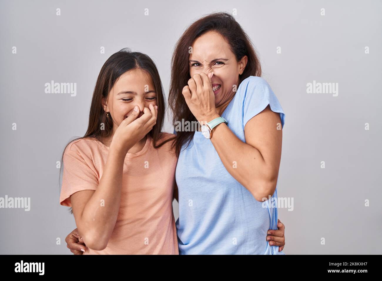Young mother and daughter standing over white background smelling
