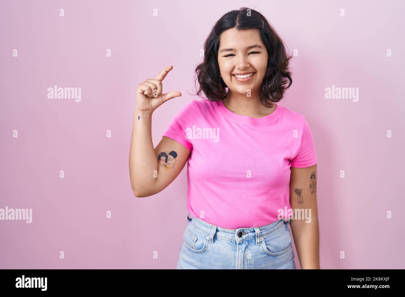 Young hispanic woman standing over pink background smiling and ...