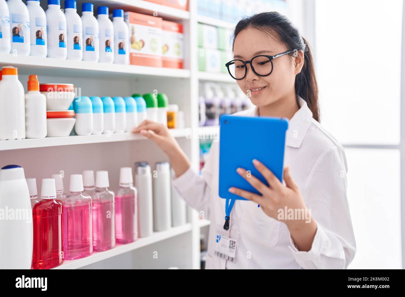 Young chinese woman pharmacist using touchpad working at pharmacy Stock ...