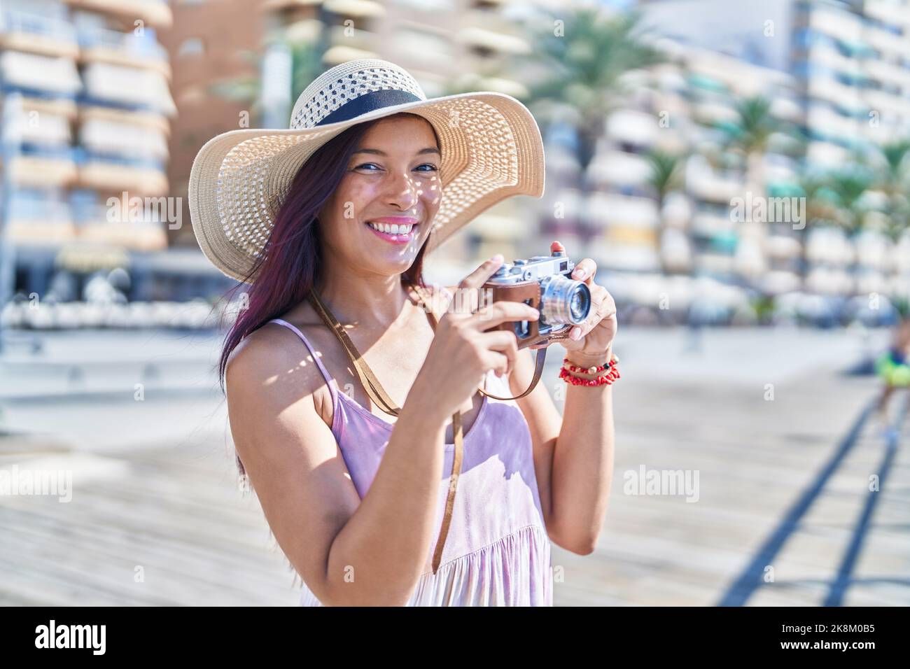 Young beautiful hispanic woman tourist using vintage camera at street Stock Photo