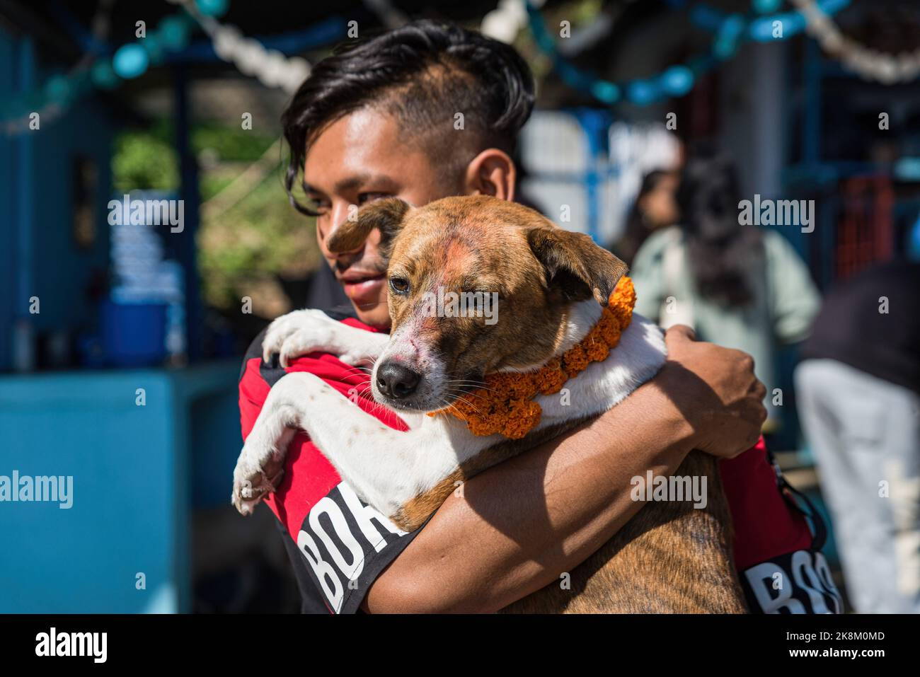 Kathmandu, Nepal. 24th Oct, 2022. A man carrying a dog with a garland