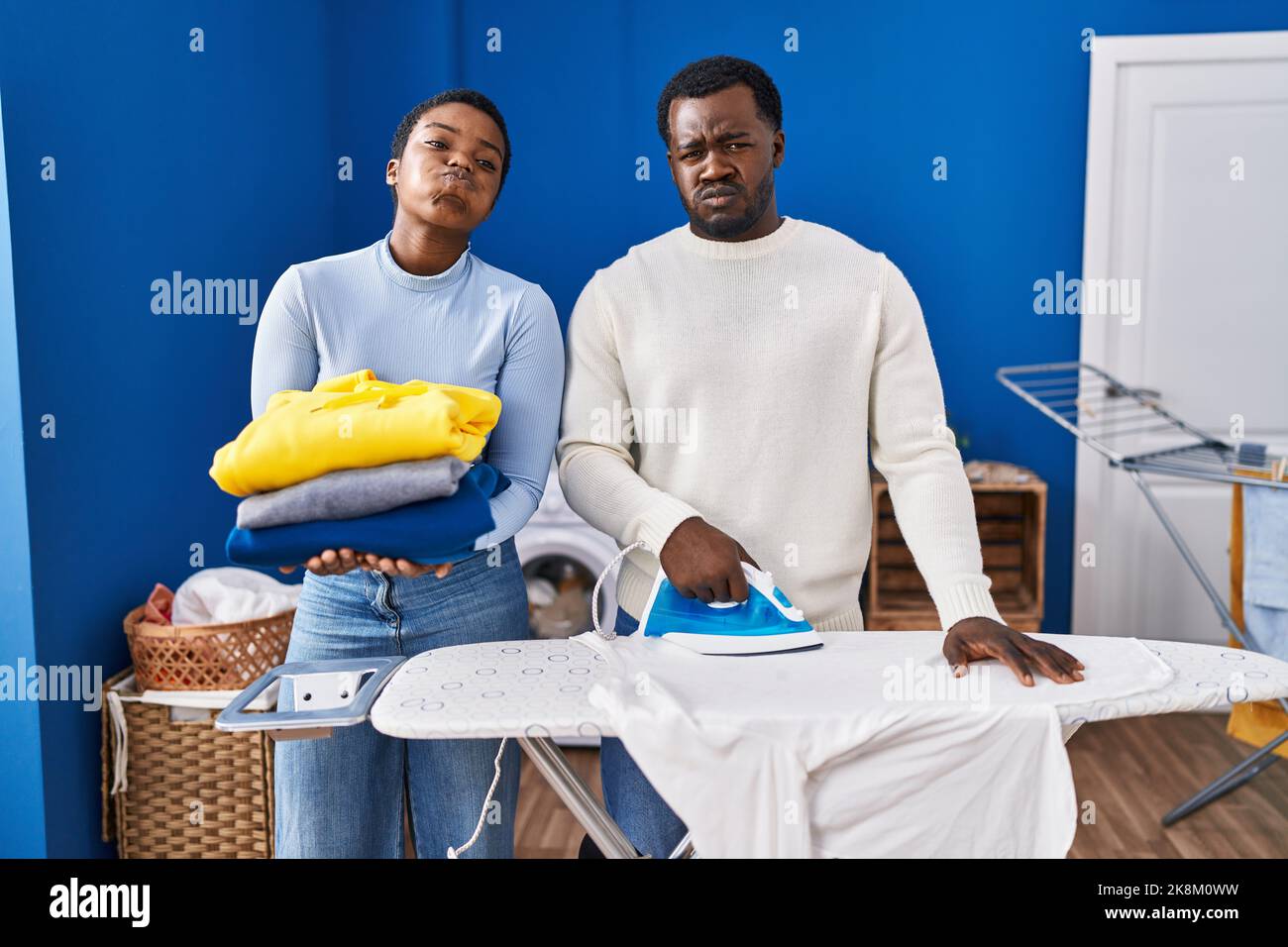 Young african american couple ironing clothes at laundry room puffing
